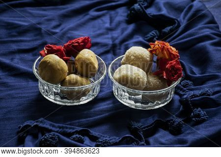 Picture Of Delicious Besan Laddu And Rawa Laddu Decorated In Bowl With Fresh Red Roses In A Blue Bac