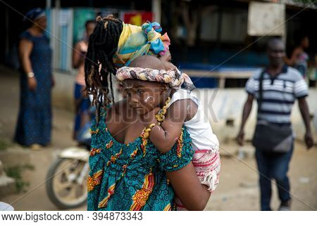 Abidjan, Cote D'ivoire - February 13, 2018: Young Unidentified Mother In Green Tank Top And Head Tie