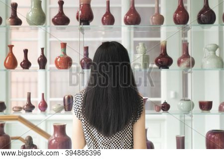 A Chinese Woman Looking At A Shelf Of Various Vases Within The Walters Art Museum In Baltimore Maryl