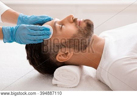 Middle Aged Handsome Man Attending Cosmetologist, Male Face Care Concept. Side View Of Unrecognizabl