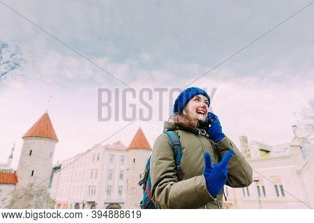 Tallinn, Estonia. Young Caucasian Woman Backpacker Tourist Enjoying Life, Smiling And Calling On Sma