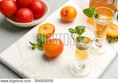Delicious Plum Liquor With Mint And Ripe Fruits On Light Table. Homemade Strong Alcoholic Beverage