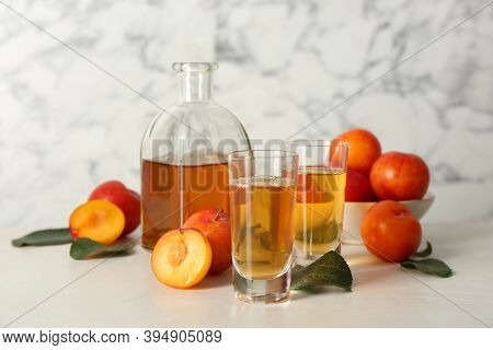 Delicious Plum Liquor And Ripe Fruits On White Table. Homemade Strong Alcoholic Beverage