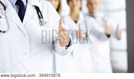 Group Of Unknown Doctors Standing As A Team With Thumbs Up In A Hospital. Medical Help, Insurance In