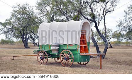 Old Wild West Covered Wagen In Texas With Mesquite Trees In Background.