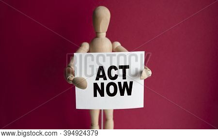 The Wooden Man Holds A White Sign With The Text Act Now In His Hands. The Content Of The Lettering H