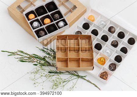 Fancy Wrapped Chocolate Candies In Sectioned Boxes Next To Empty Ones