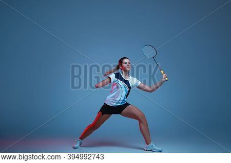 On The Run. Beautiful Handicap Woman Practicing In Badminton Isolated On Blue Background In Neon Lig