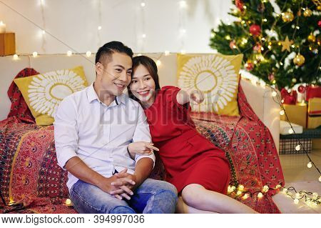 Beautiful Smiling Young Asian Couple Sitting On The Floor In Living Room And Watching Tv