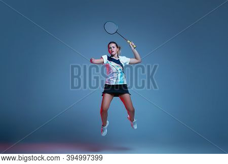 On The Run. Beautiful Handicap Woman Practicing In Badminton Isolated On Blue Background In Neon Lig