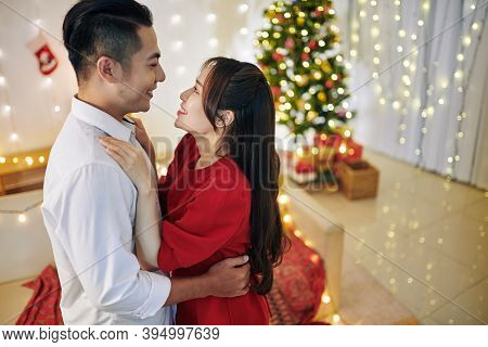 Happy Young Asian Boyfriend And Girlfriend Hugging And Looking At Each Other When Standing In Room D