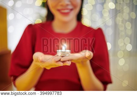 Smiling Young Woman Holding Small Burning Candle And Making A Wish