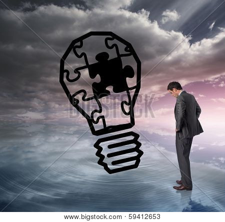 Businessman with hands on hips against light bulb graphic on colourful horizon