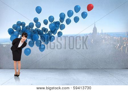 Surpised businesswoman bending against many colourful balloons in room with city on wall