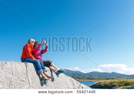 Two women taking photo of Norwegian landscape