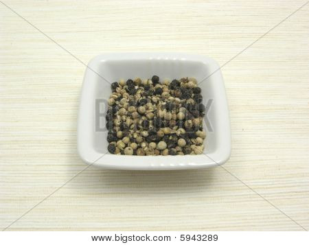 ชามของเครื่องลายครามด้วย Peppercorns บน Underlay สีเบจ