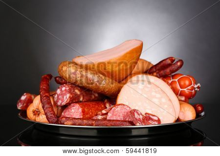 Lot of different sausages on salver on grey background
