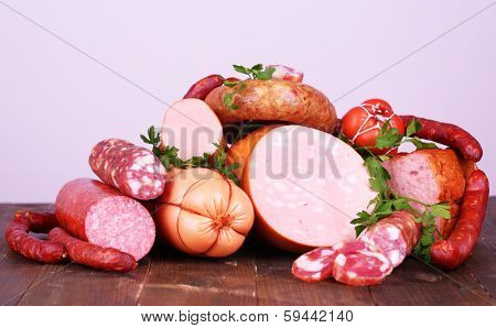 Lot of different sausages on wooden table on grey background
