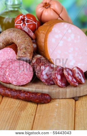 Different sausages on wooden table on natural background