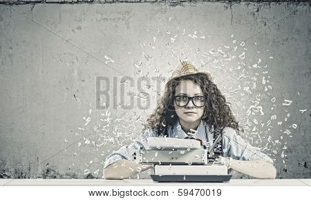 Young funny woman in glasses using typewriter