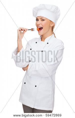 cooking and food concept - smiling female chef, cook or baker with fork and tomato