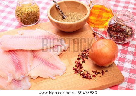 Raw fish tilapia on cutting board and spices