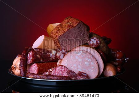 Lot of different sausages on salver on dark colorful background