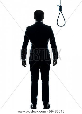 one caucasian business man rear view standing in front of hangman's noose in silhouette studio isolated on white background
