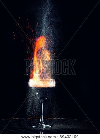 Flaming cocktail with gray pepper on dark background