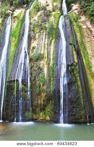 Unusual three-jet waterfall. Three parallel streams of water running down the steep slope and fall in oval pool