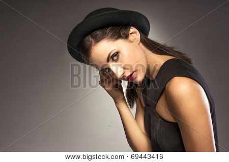 elegant woman weating hat and black dress on grey