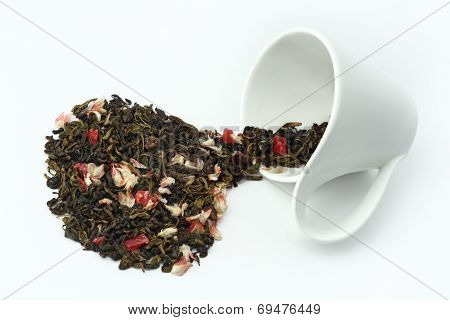 Tea concept. Tea leaves spilled from an overturned cup on white background