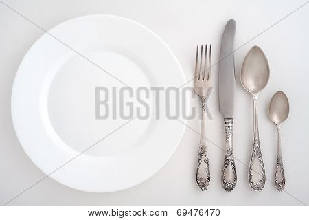 Vintage cutlery set with fork, knife, spoon and plate. Overhead view.