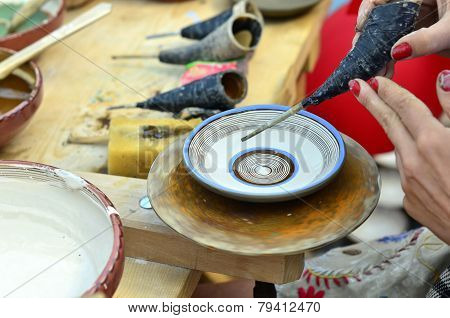 BRASOV, ROMANIA - AUGUST 27, 2014: Woman painting traditional plates at a fair with specific design