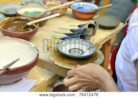 BRASOV, ROMANIA - AUGUST 27, 2014: Woman painting traditional plates at a fair with specific design
