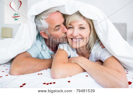 Closeup of mature man kissing womans cheek in bed against cute valentines message