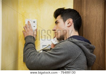 Young man answering the intercom in an apartment