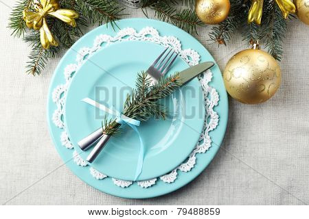 Christmas table setting in blue, golden and whitec olors on grey tablecloth background
