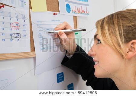 Businesswoman Writing On Weekly Time Sheet