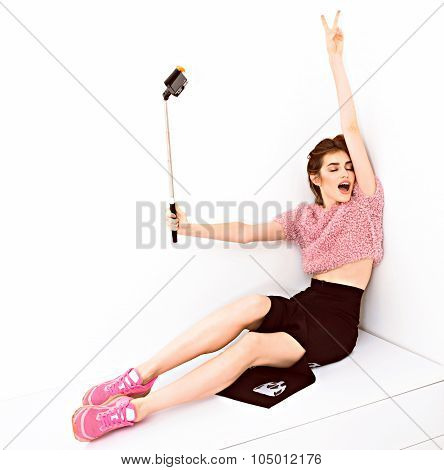 Young fashion model woman taking a selfie with phone on monopod