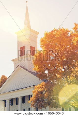 Traditional American white church in the fall with nautural sun flare