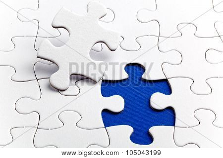 Plain white jigsaw puzzle on Blue background autism awerness symbol