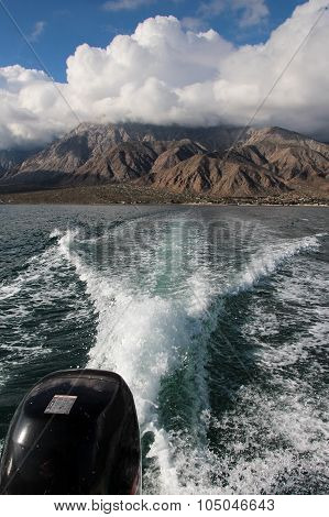 Boat wake in sea with mountains in background