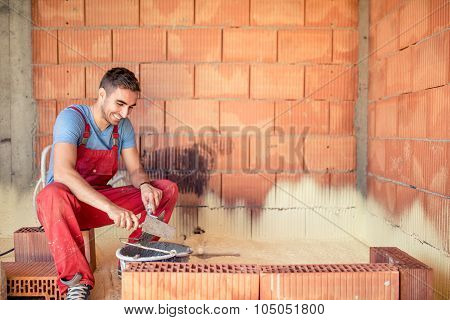 Construction Mason Worker, Bricklayer Building Brick Walls With Spatula And Mortar