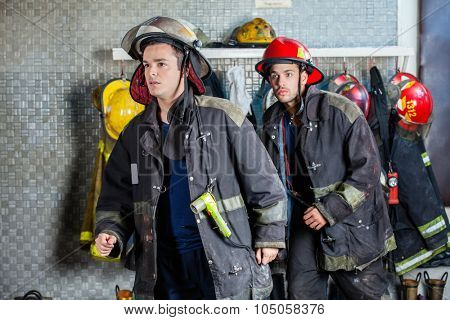 Young male firefighters in uniforms walking at fire station