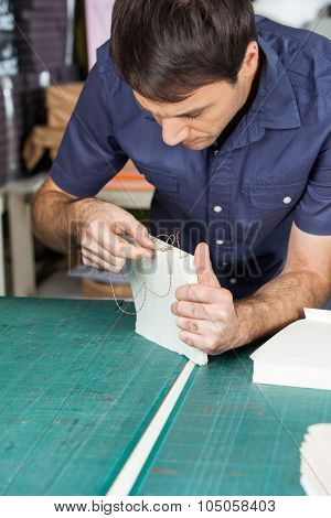 Mid adult male worker binding pages at table in paper factory