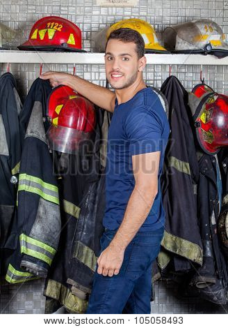Side view portrait of confident fireman removing uniform hanging at fire station