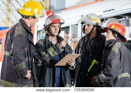 Male firefighter gesturing while discussing with colleagues at fire station