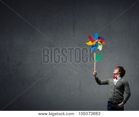 Young happy guy in casual with colorful windmill in hand