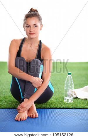 Beautiful young woman relaxing after exerscises on the grass 